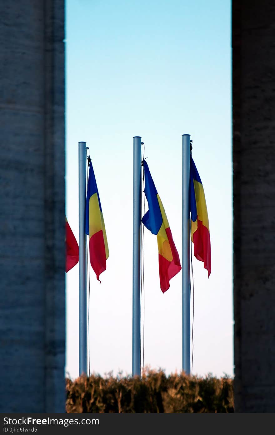 Three Blue-yellow-and-red Flags on Gray Pole