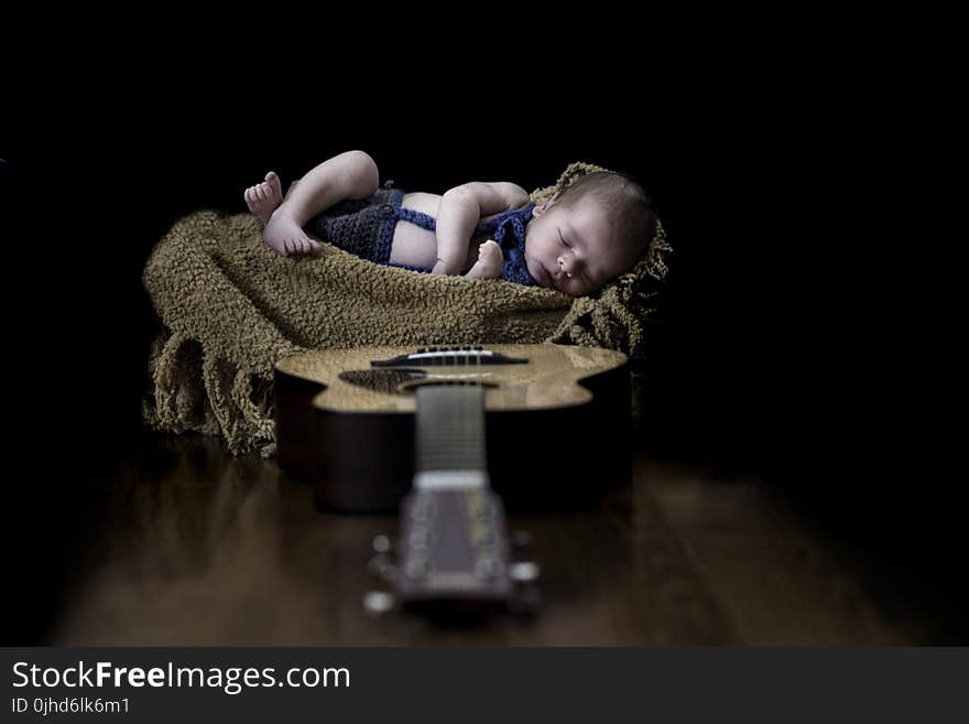 Baby on Beige Textile Near Brown Dreadnought Acoustic Guitar