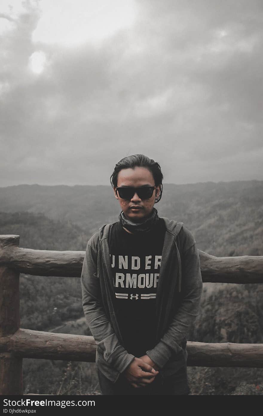 Man in Black Top and Grey Hoodie Jacket Standing Beside Brown Wooden