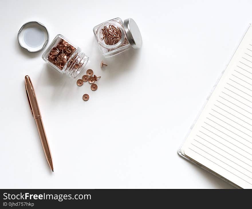 Bunch of Thumbtacks With Two Clear Glass Containers on White Surface