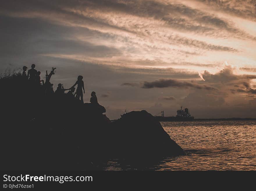 Silhouette of People on Mountain Near Body of Water