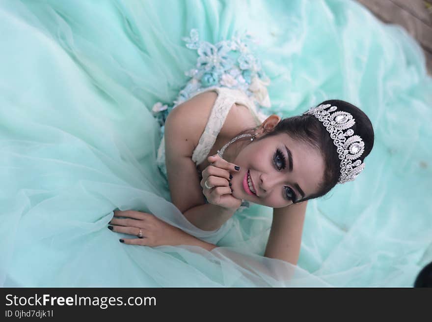 Woman Wears Teal Chiffon Gown and Crown