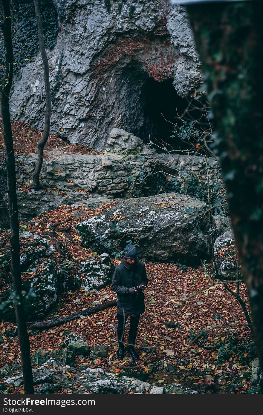 Man In Black Coat Standing Near Cave