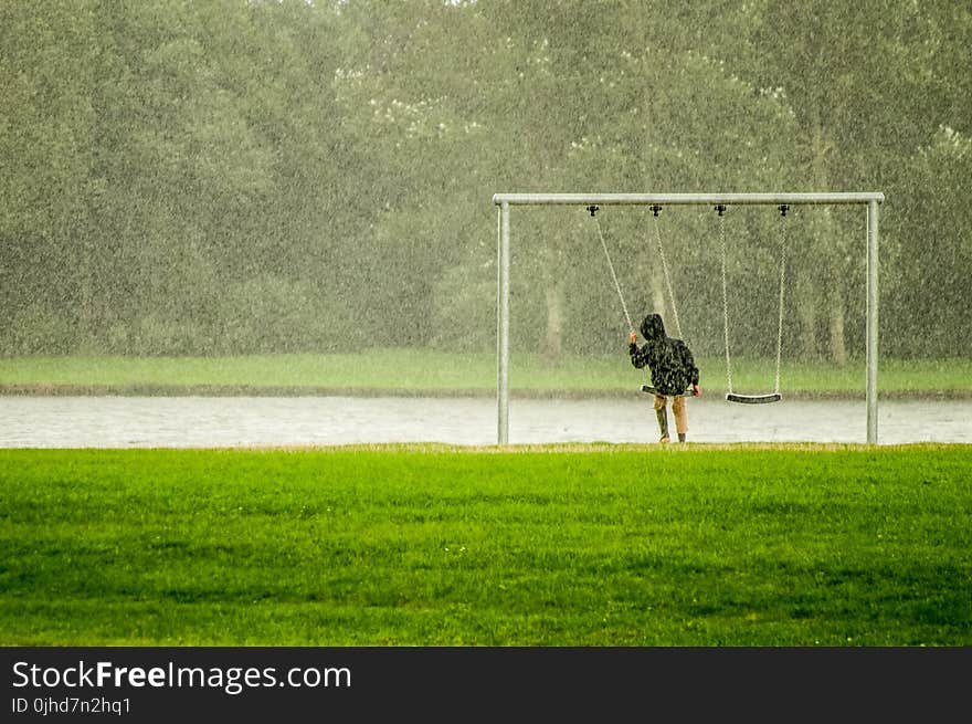 Person In Black Hoodie Riding Swing While Raining