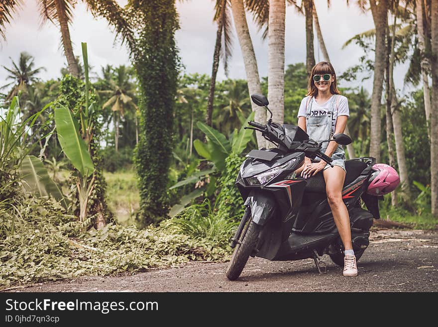 Woman in Gray Shirt Riding Black Motor Scooter