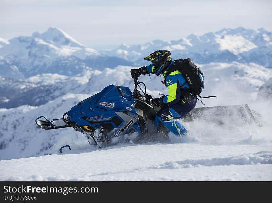 Man In Blue And Green Long-sleeved Suit Riding On Snowmobile