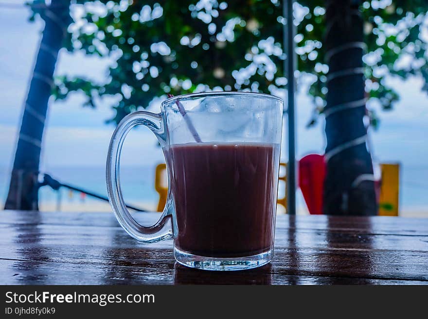 Clear Glass Mug With Beverage on Brown Wooden Table