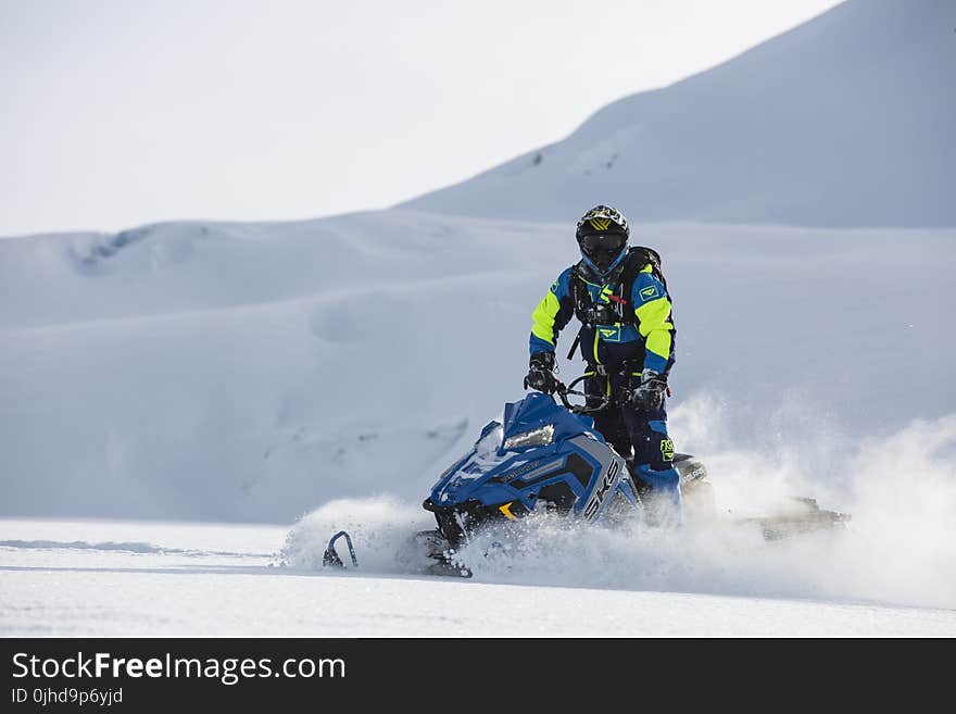 Person Rides on Blue Snowmobile at Daytime