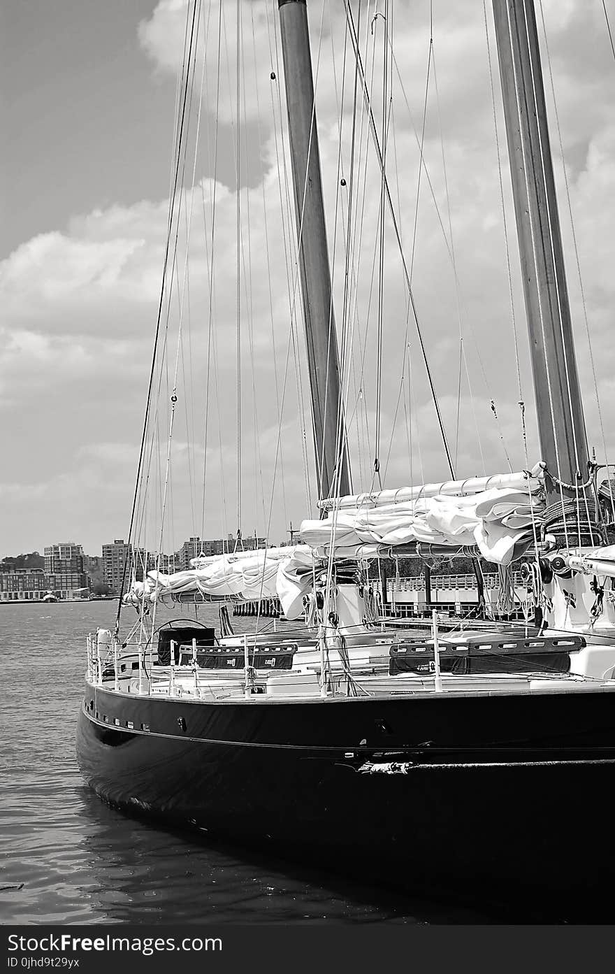 Grayscale Photo of Ship Near High-rise Mountains