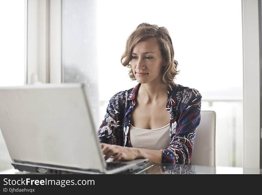 Woman in Blue Floral Top Sitting While Using Laptop