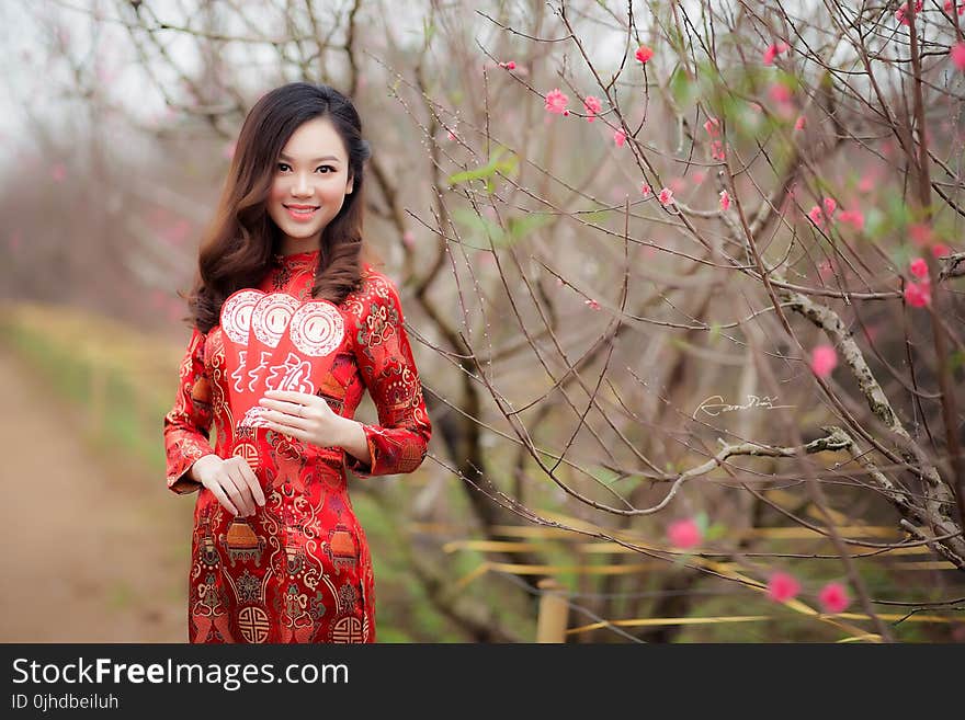 Woman in Black and Red Floral Long-sleeved Shirt Stands Near Green Plant