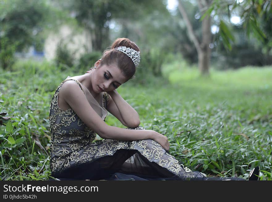 Woman Wearing Brown and White Sleeveless Floral Embroidered Dress Sitting on Green Grass Field