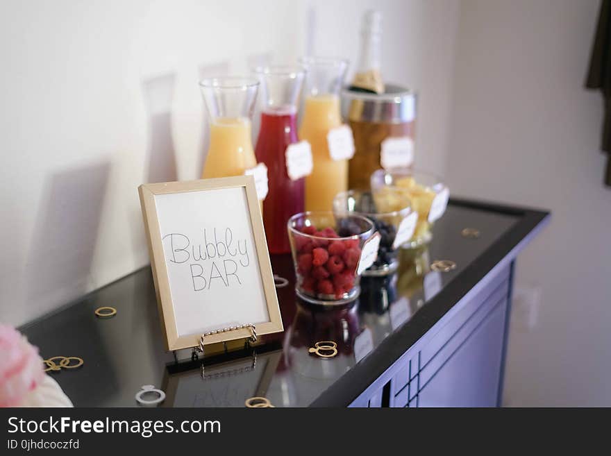 Bubbly Bar Sign With Several Assorted-color Liquid With Bottles on Top of Black Wooden Table