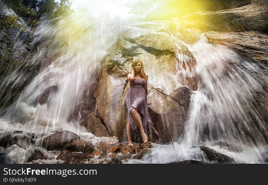 Woman in Gray Strapless Long Dress Standing Under Waterfalls