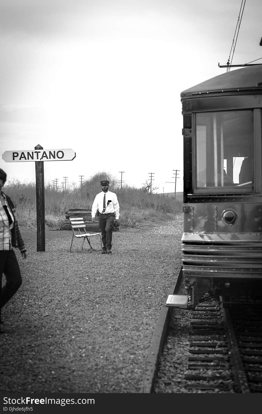 Grayscale Photo of Man Walking Near Train