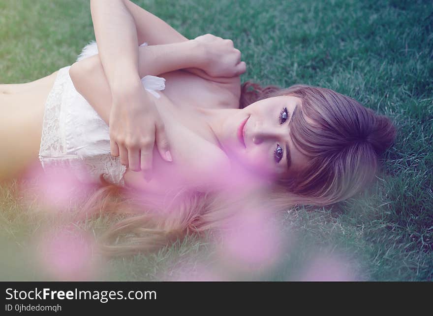 Photo of a Woman Lying on Green Wearing White Top