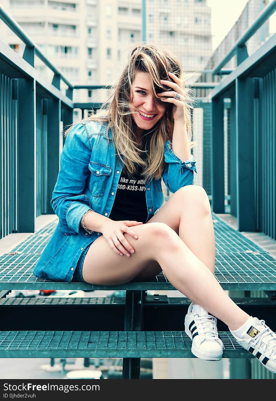 Woman Wearing Blue Denim Button-up Jacket and Black Printed Shirt With Pair of White Adidas Superstar Shoes