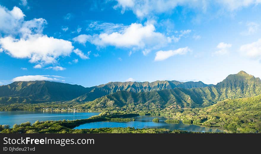 Green Forested Mountain Range Under Blue Sky With Clouds