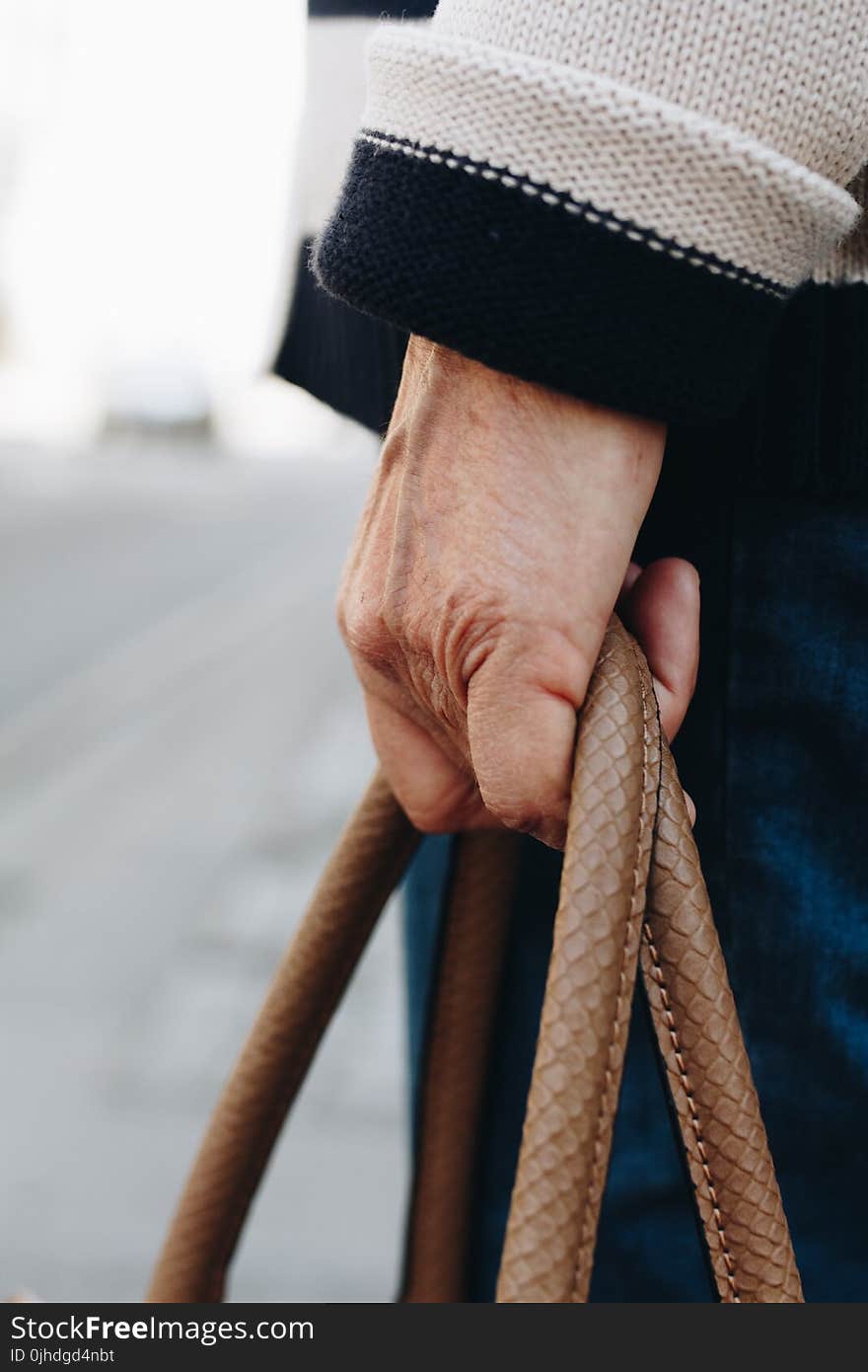 Person in White Sweater Holding Brown Handbag