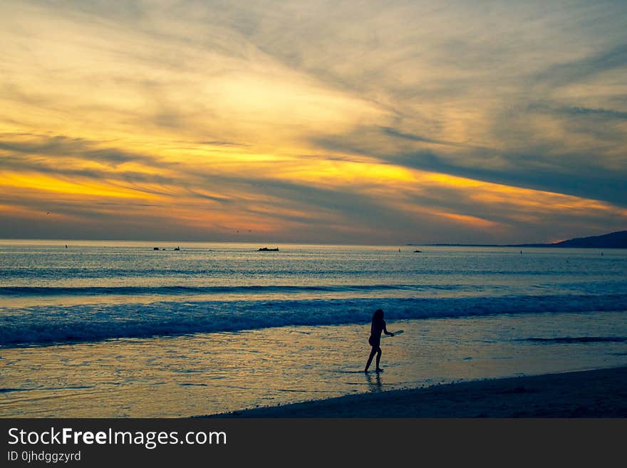 Photo of Person Walking on Beach Shore