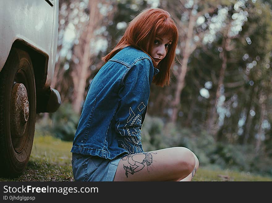 Photo of a Woman in Blue Denim Jacket Sitting Near White Car