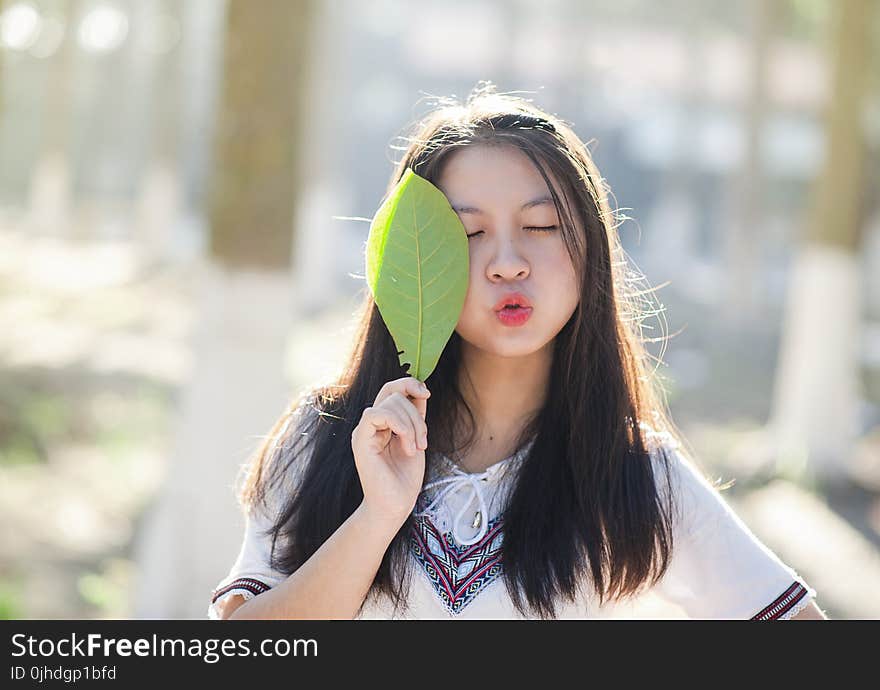 Woman Holding Green Leaf With Lips Kissing and Closing Eyes