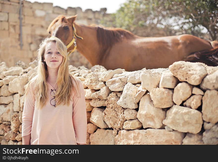 Woman Wearing Pink V-neck 3/4 Sleeved Shirt With Eyeglasses Standing in Front of Brown Horse