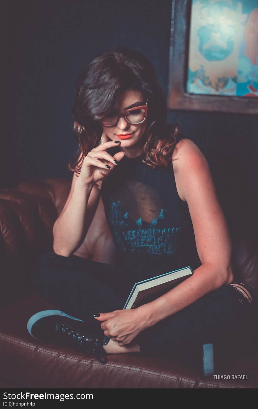 Woman Wearing Black Graphic Printed Tank Top and Pants Sitting on Brown Leather Sofa