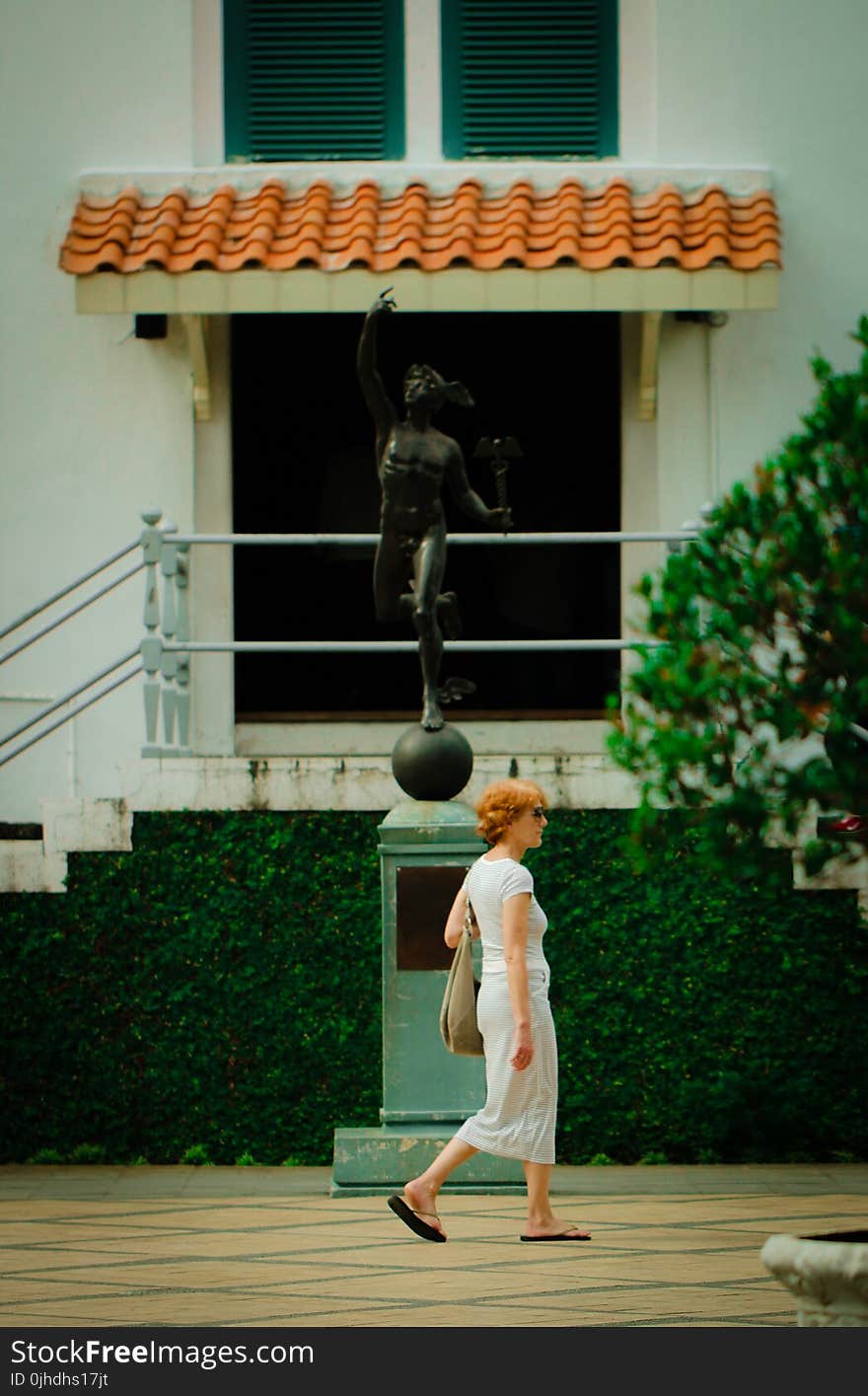 Woman Walking in Front Of Statue