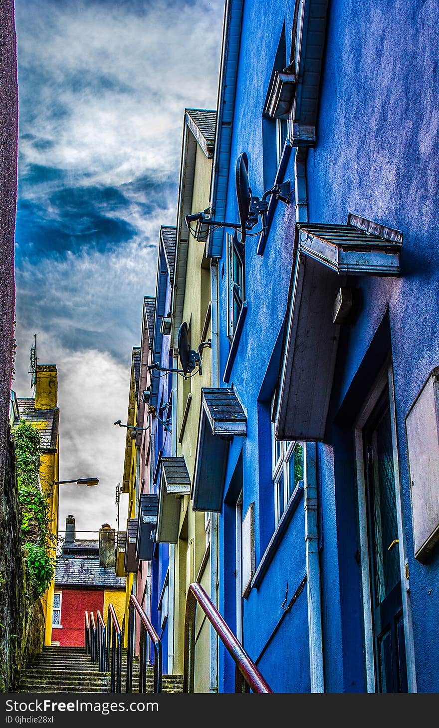 Concrete Steps Beside Blue, Yellow, and Purple Concrete Structures Under Cloudy Sky