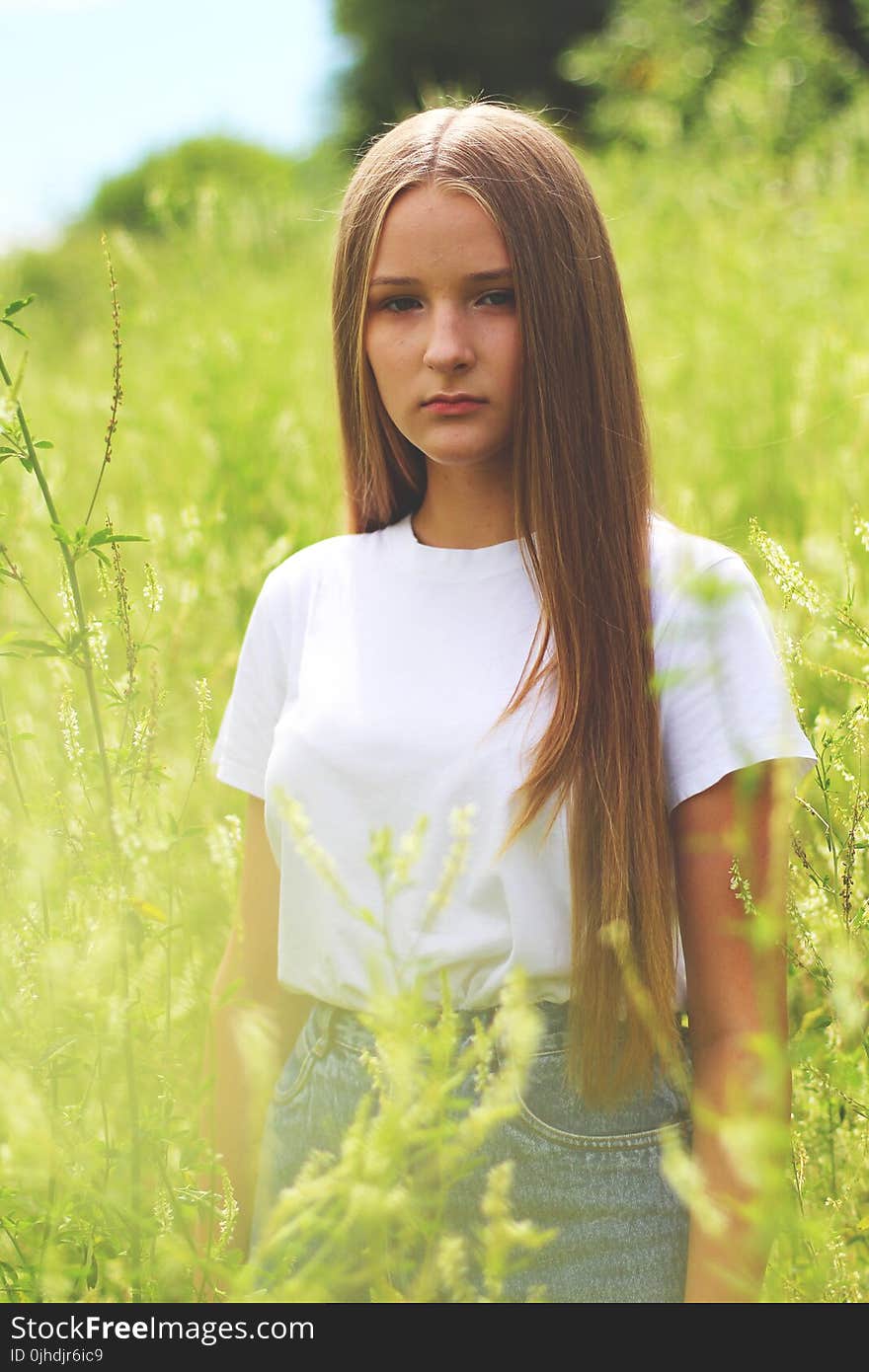 Woman Wearing White Shirt and Gray Denim Bottoms on Green Grass Field