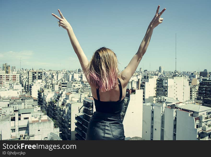 Woman Standing on Rooftop Putting Hands in the Air Under Clear Sky