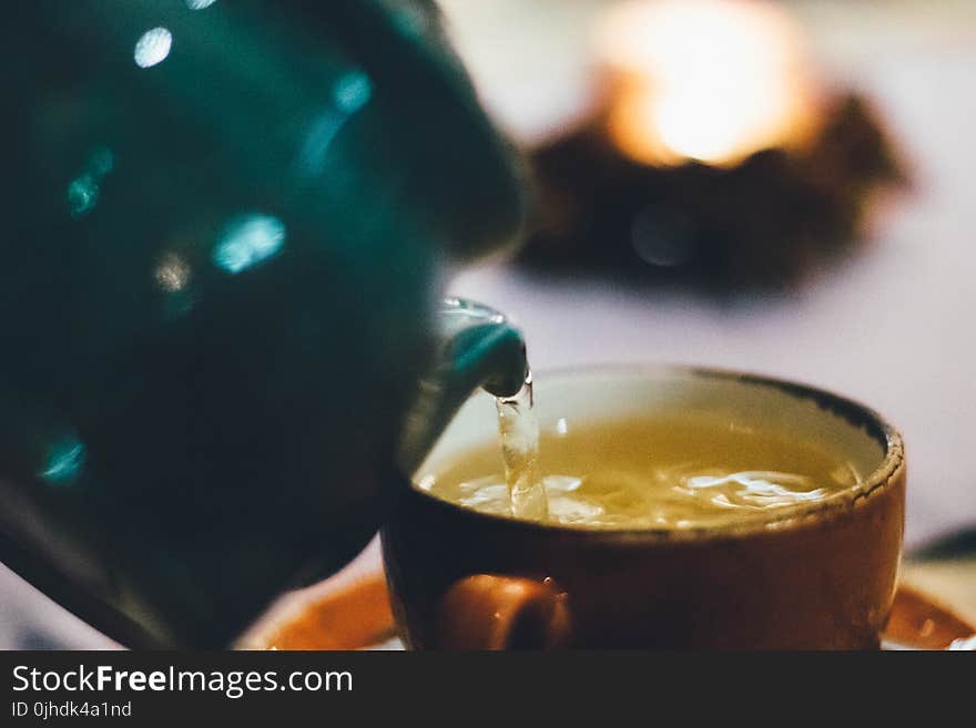 Person Pouring Liquid Into Brown Ceramic Cup