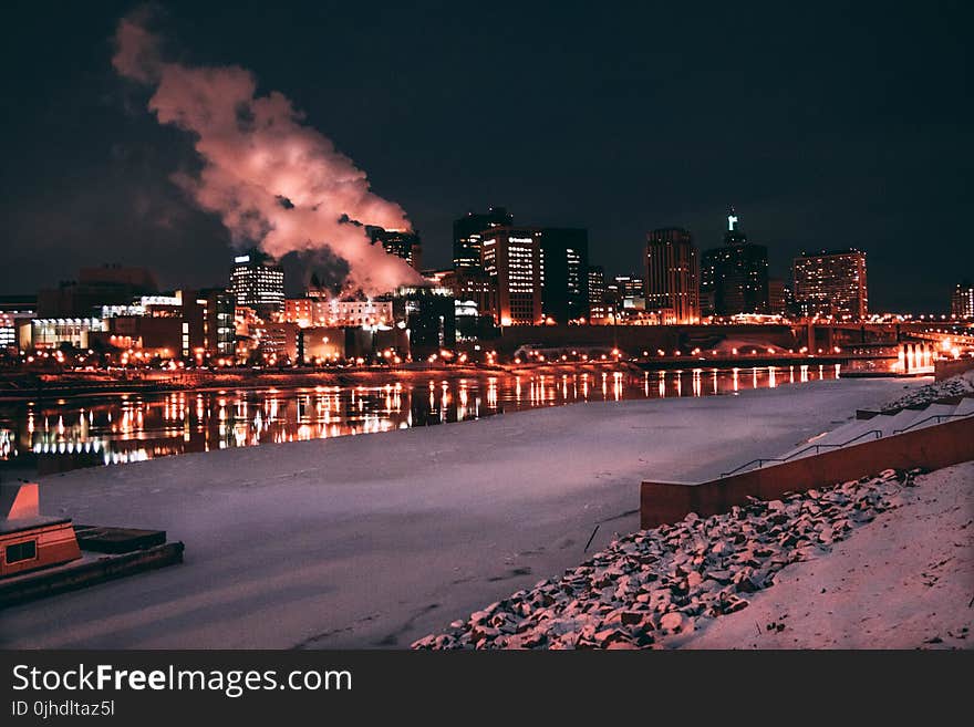 Low Light Photo of Lighted Buildings in Front of Body of Water