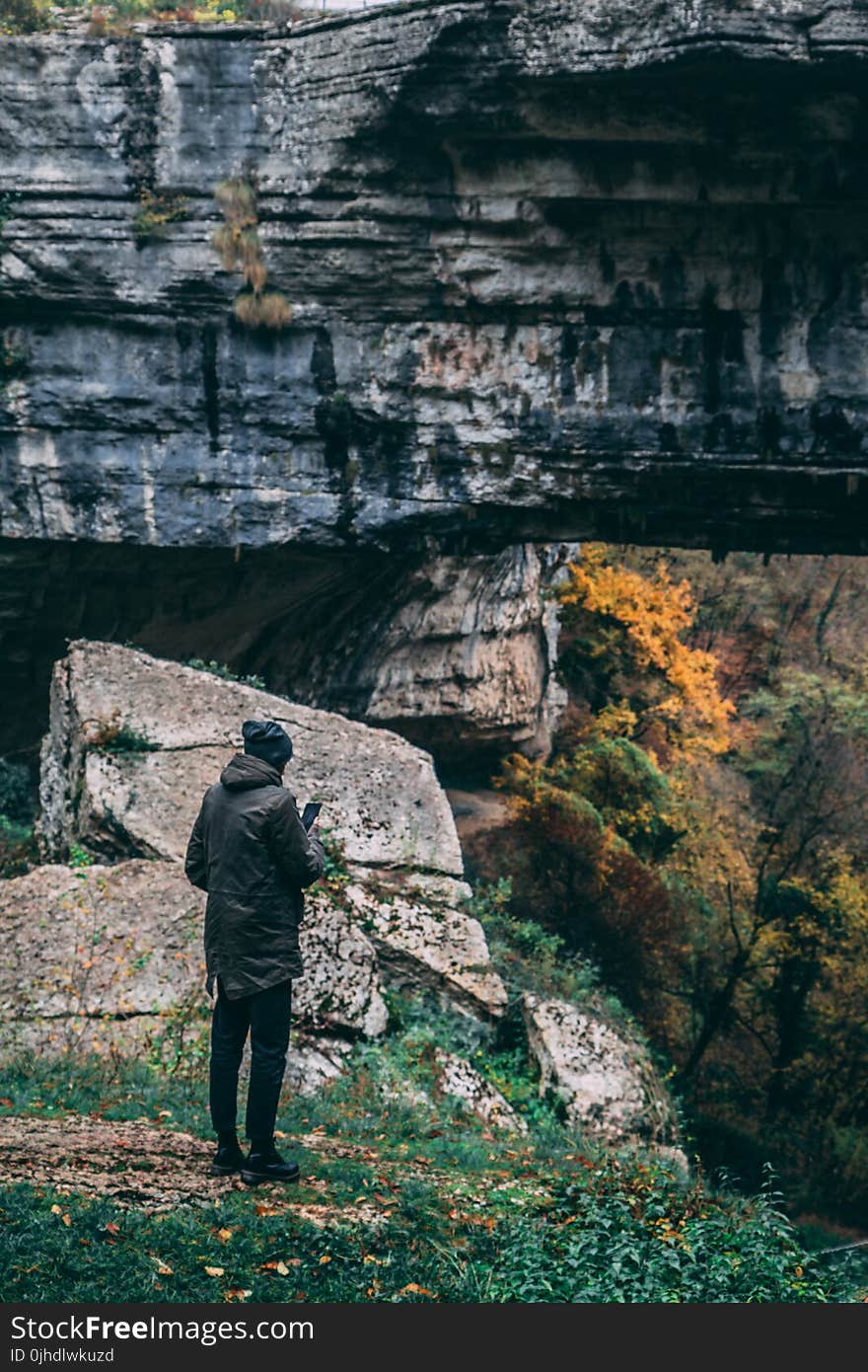 Man Standing in Front of Rock Formation