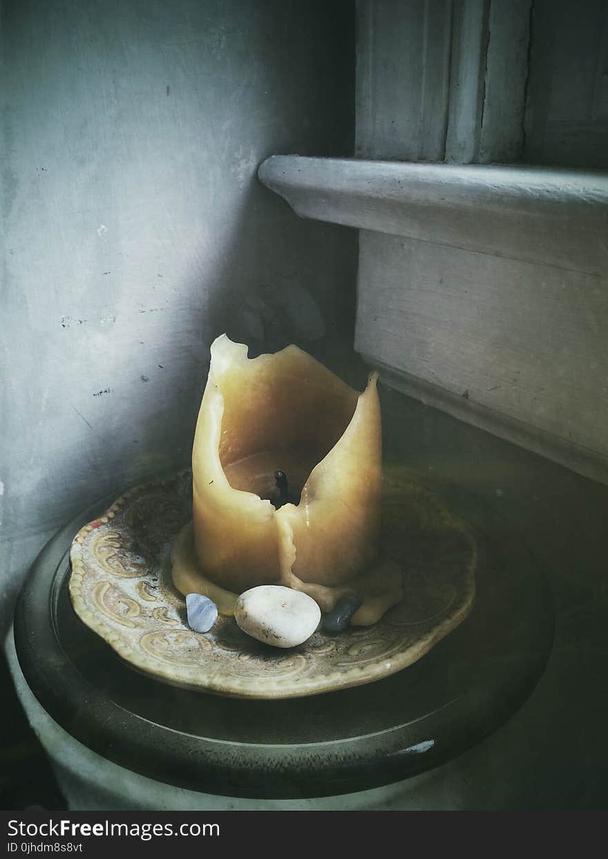 Beige Candle on Beige Saucer Plate Beside Polished Pebbles Near Window