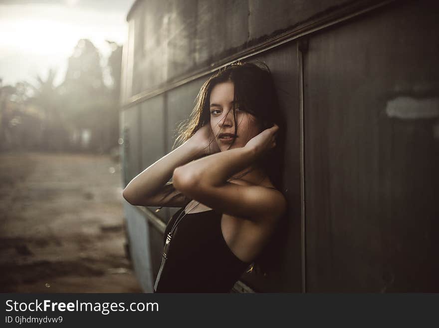 Woman in Black Spaghetti Top Holding Hair Leaning on Vehicle