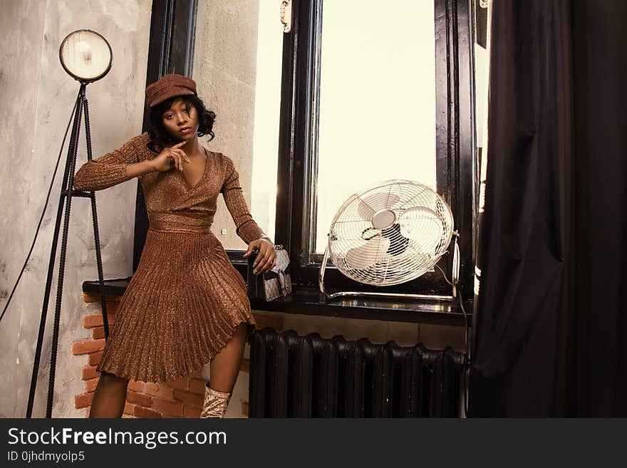 Woman Wearing Brown Dress Near Fan Standing Beside Table at Daytime