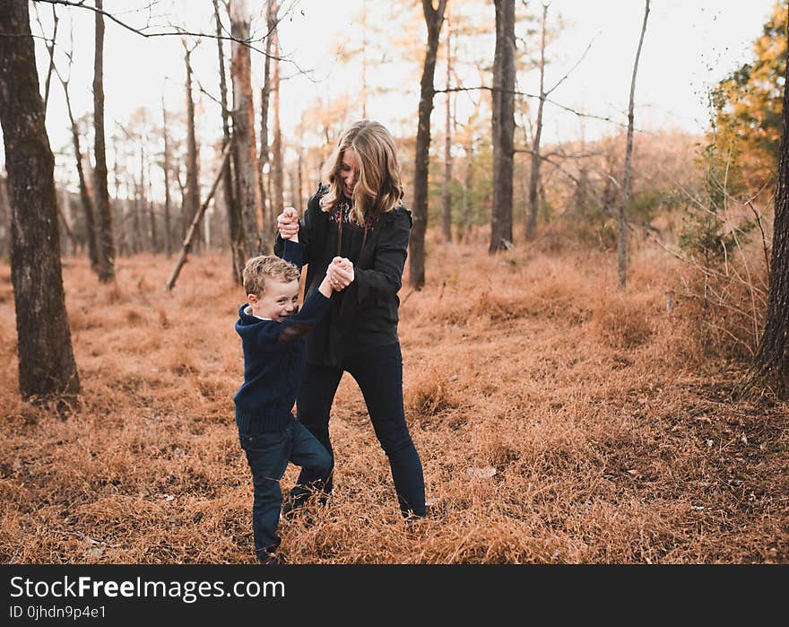 Woman Wearing Black Jacket Playing With Young Boy