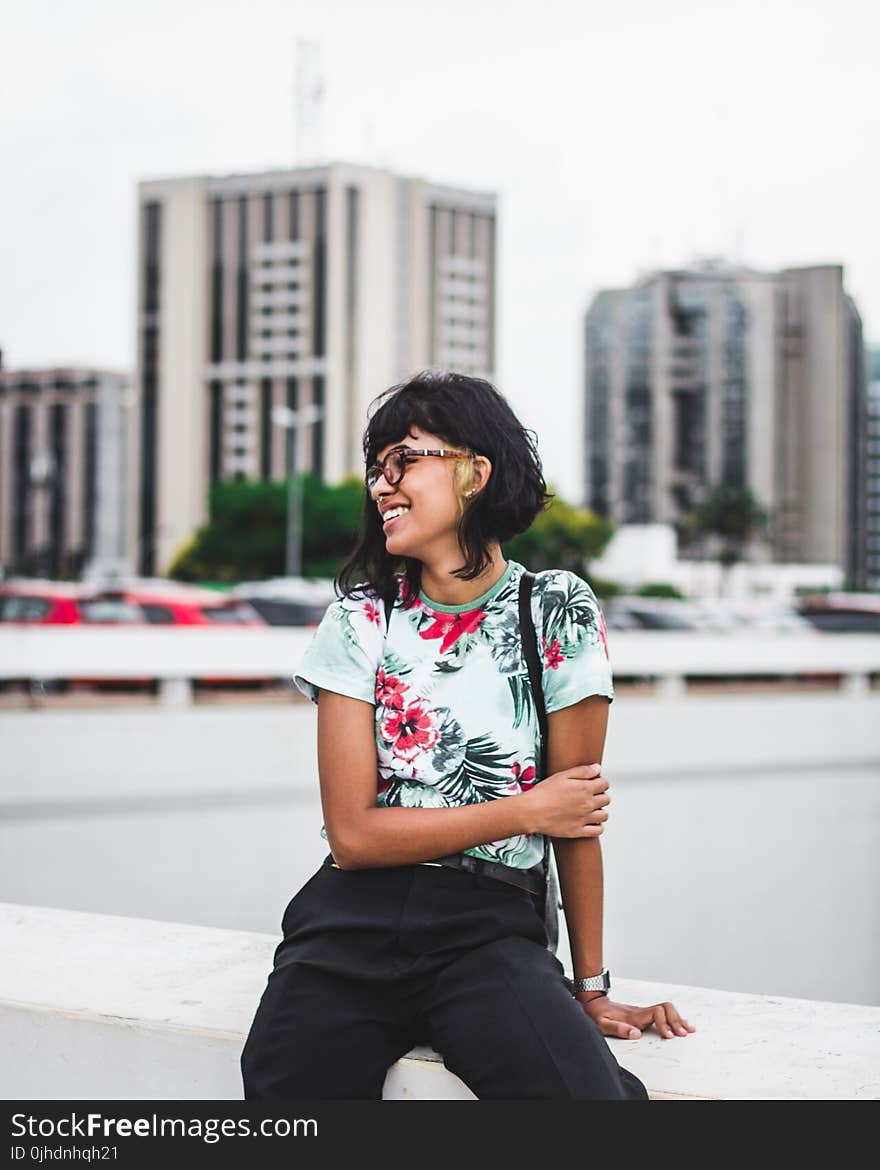 Photography of a Woman Sitting on a Ledge