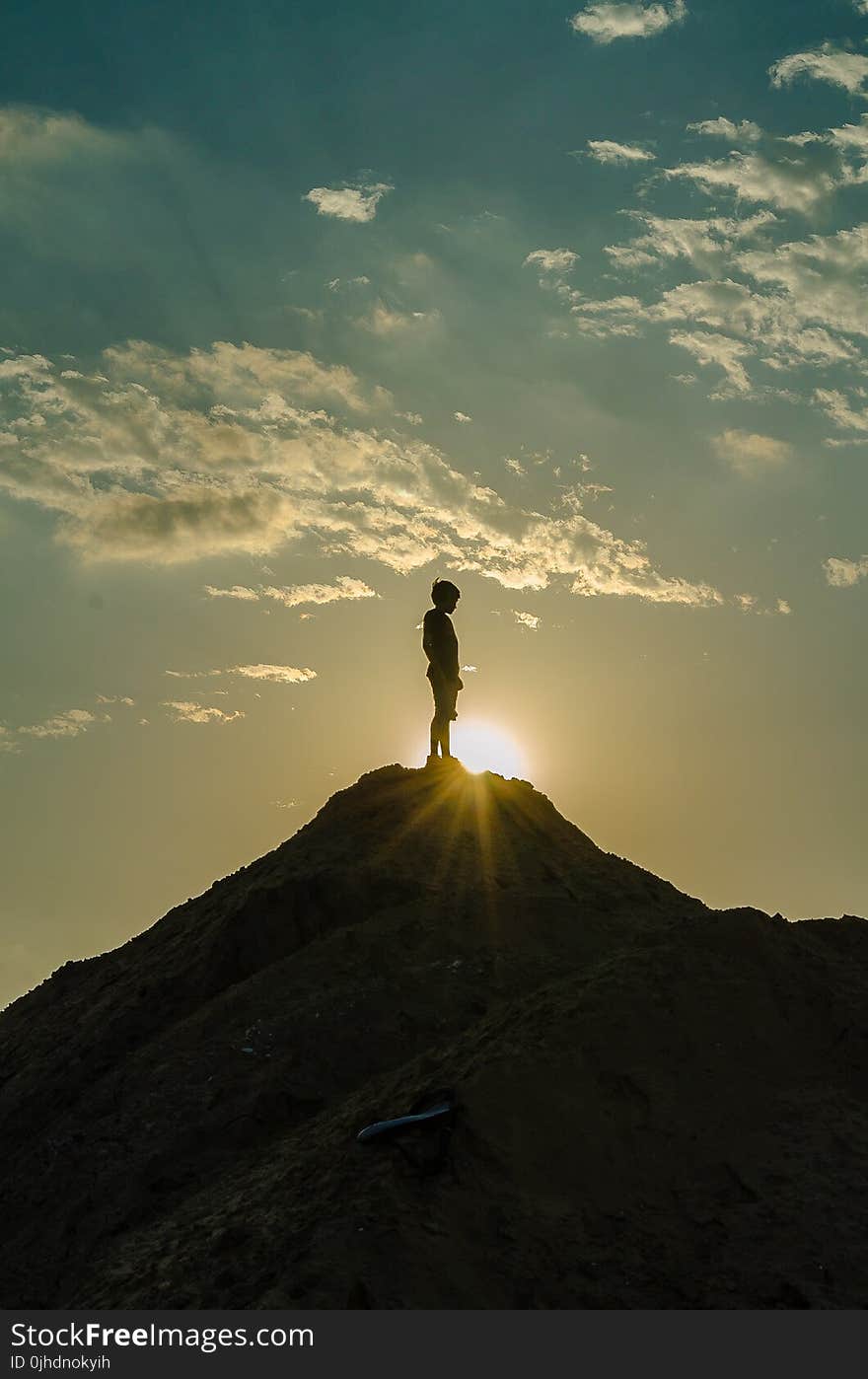 Silhouette of a Man Standing on a Mountain