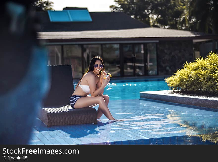 Selective Focus Photography of Woman Wearing Black and White Bikini Sitting Brown Chair