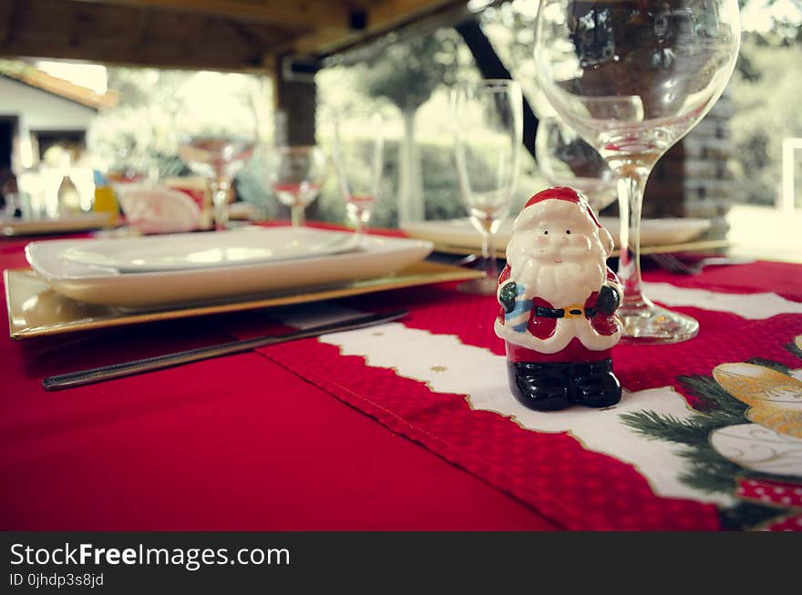 Santa Claus Ceramic Figurine Next to Wine Glasses and White Ceramic Plate