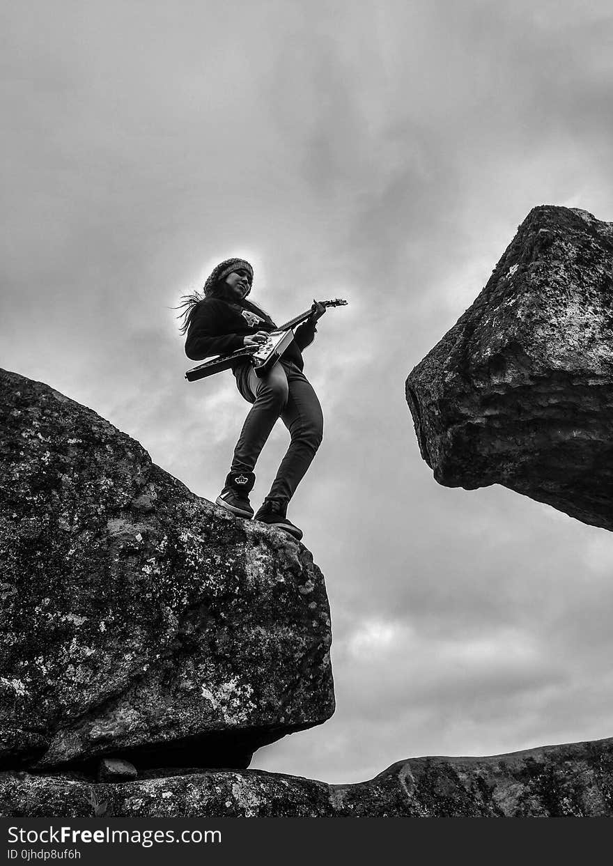 Woman Playing Electric Guitar on Top of Rock Formation