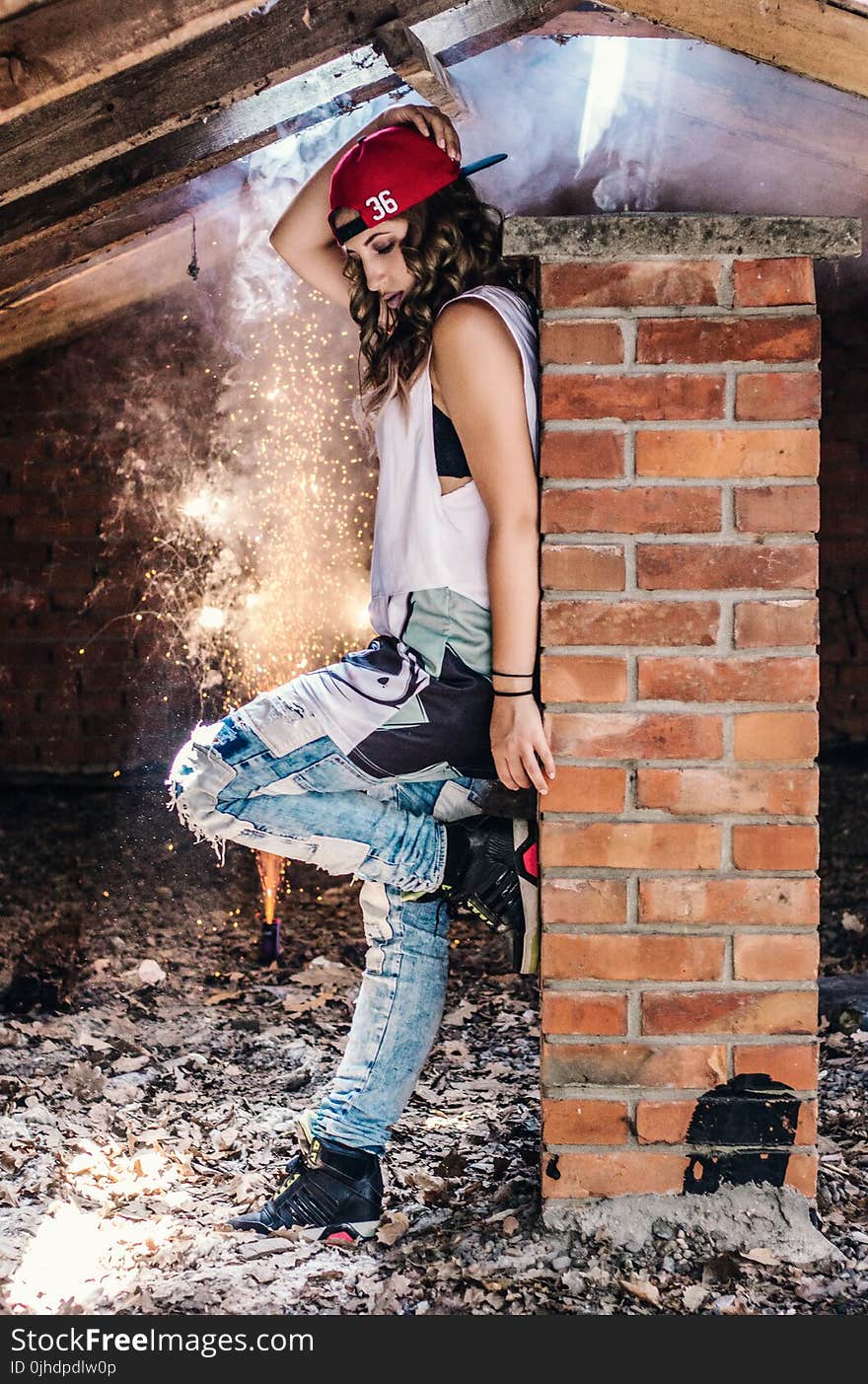 Woman Wearing White Tank Top Leaning on Brown Brick Wall