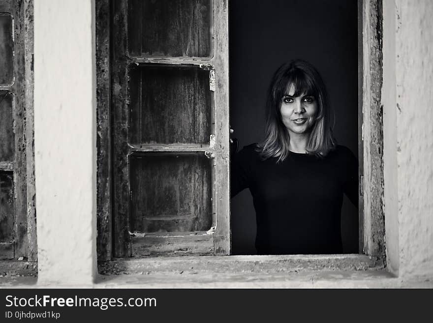 Gray Scale Photo of Woman in Window