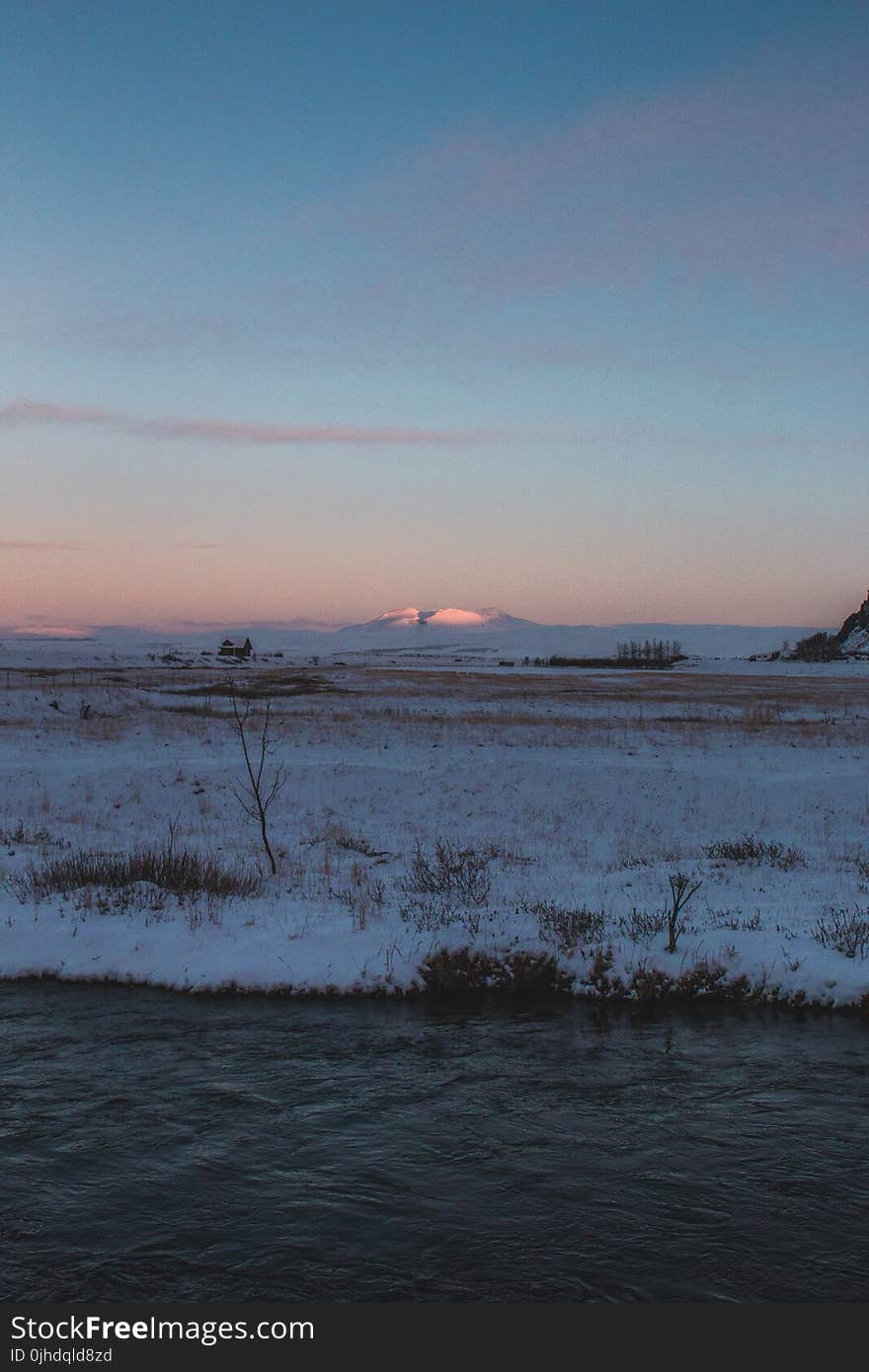 Snow-covered Filed Near Body of Water