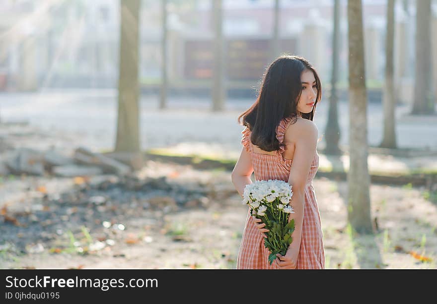 Woman Wearing Orange Sleeveless Dress Holding a Bouquet of Flowers