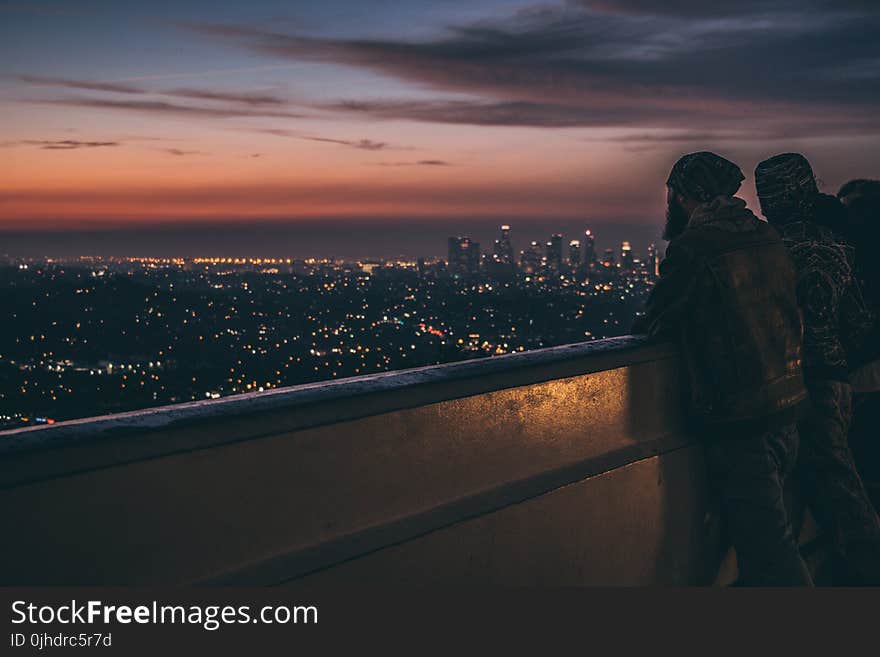 Silhouette of People Leaning on Metal Railings