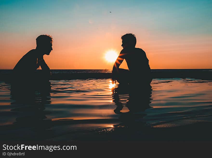 Photo of Two Men on Seashore during Sunset